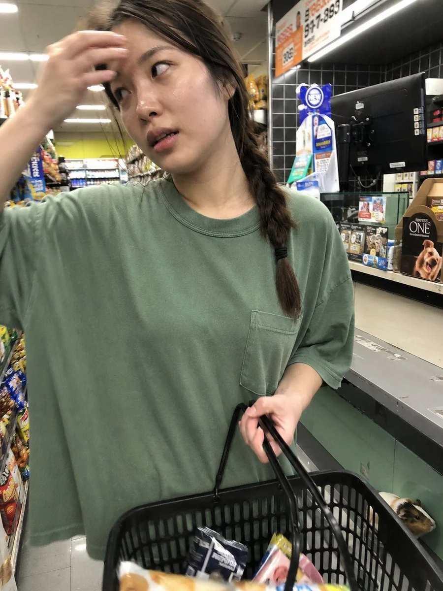 A candid iPhone-style convenience store portrait of a young Korean woman at checkout under bright fluorescent lighting