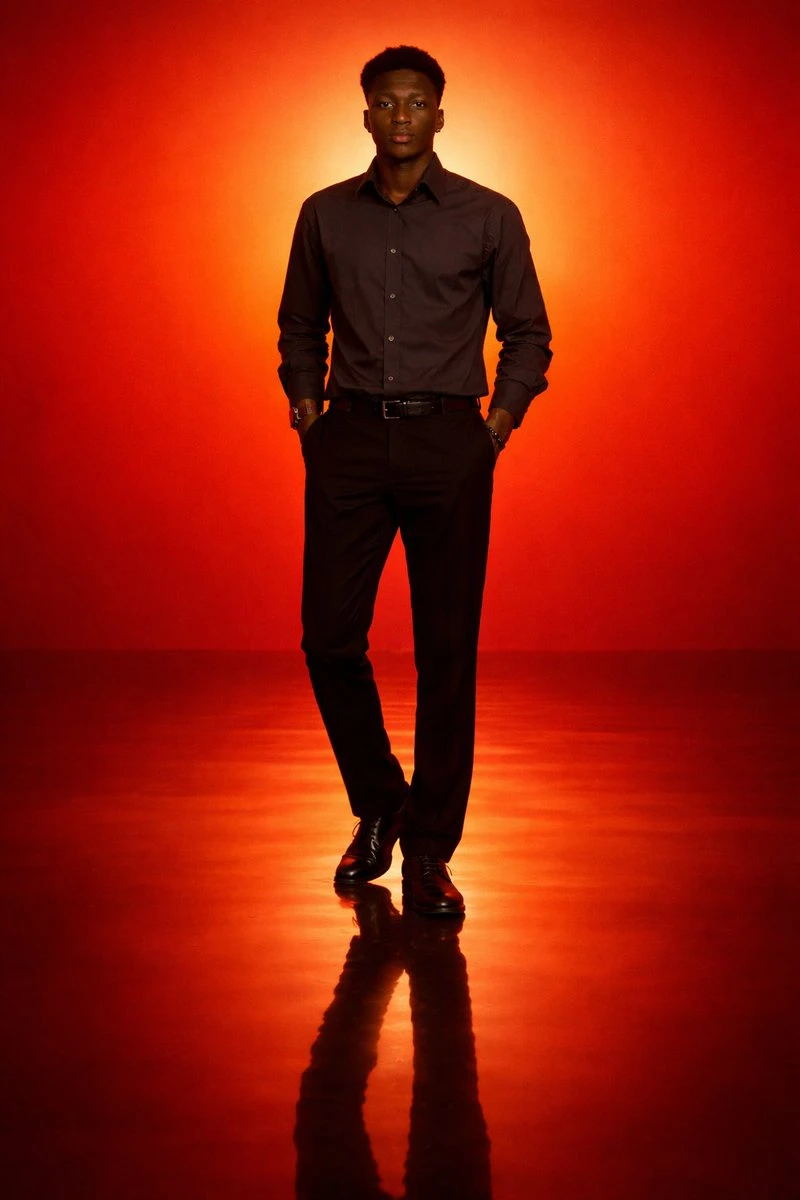 A solitary man stands against a vibrant orange to red gradient backdrop, featuring strong silhouette lighting and a reflective glossy floor