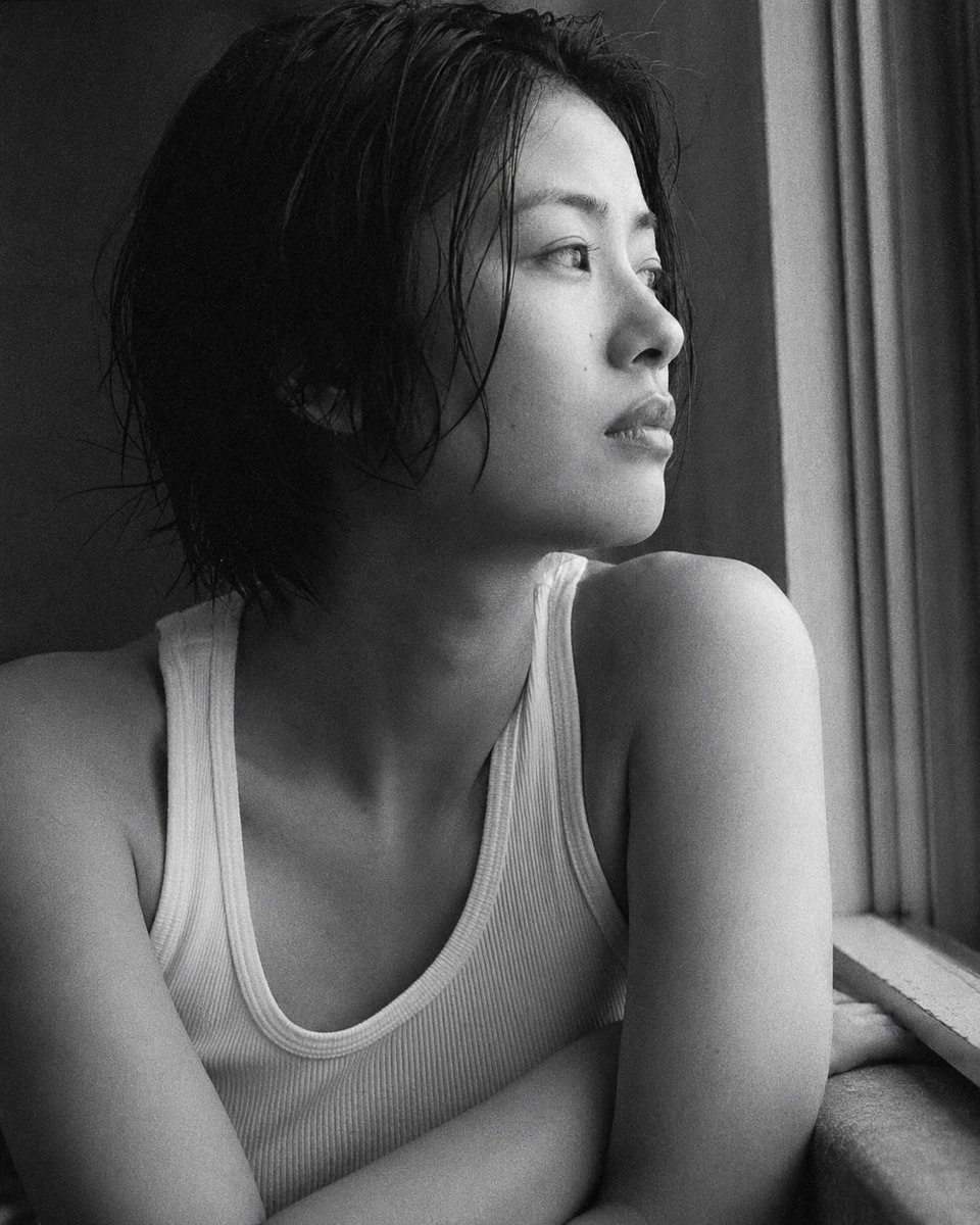 Black-and-white Japanese portrait of a young man by a window with soft side light and film grain
