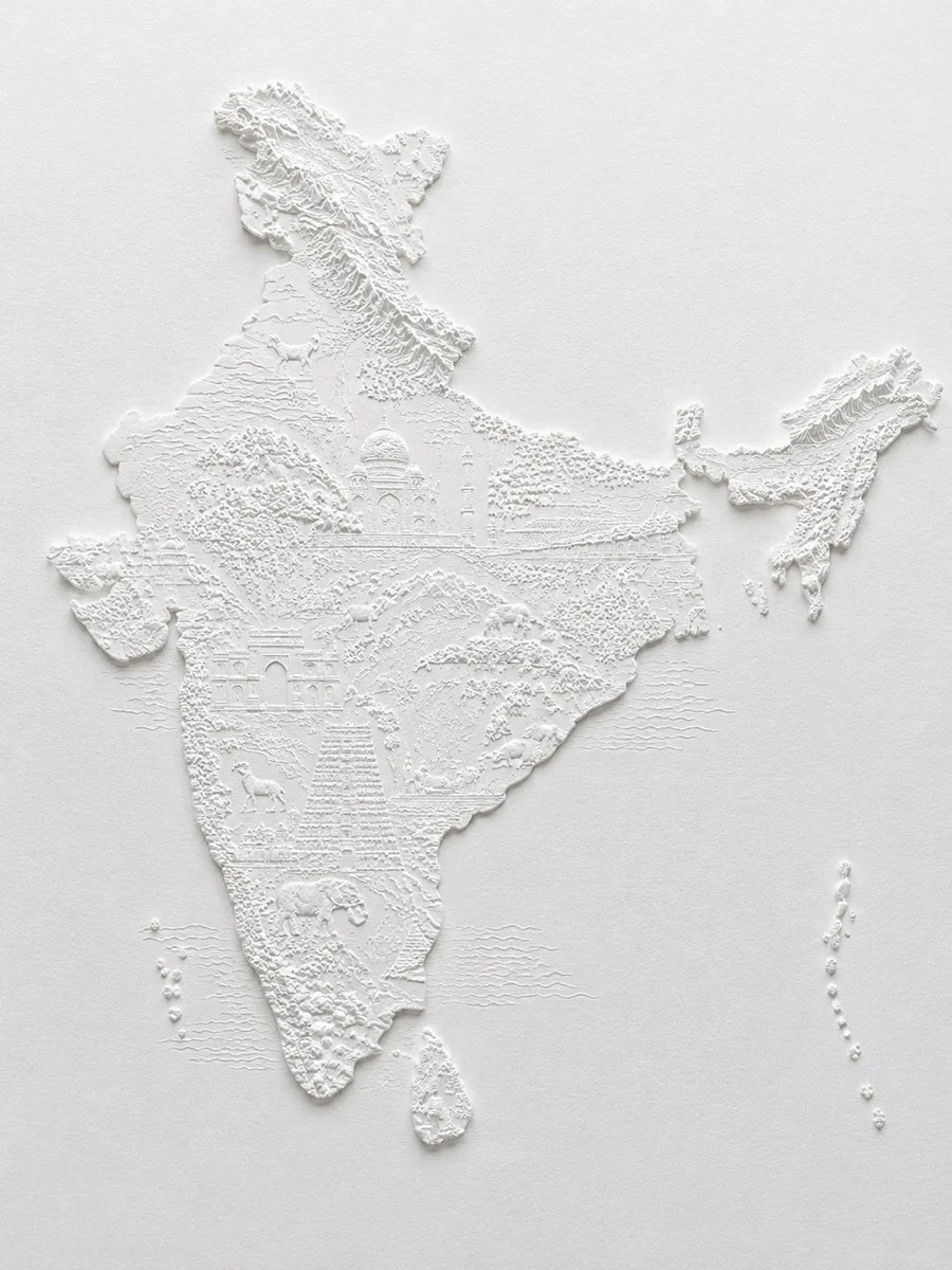 A monochrome white bas-relief paper sculpture map of India with raised landforms, warm paper texture, and crisp shadows